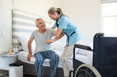 caregiver assisting senior man to get up from bed